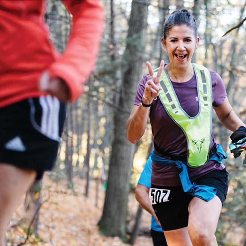 photo of smiling runner in woods giving the peace sign