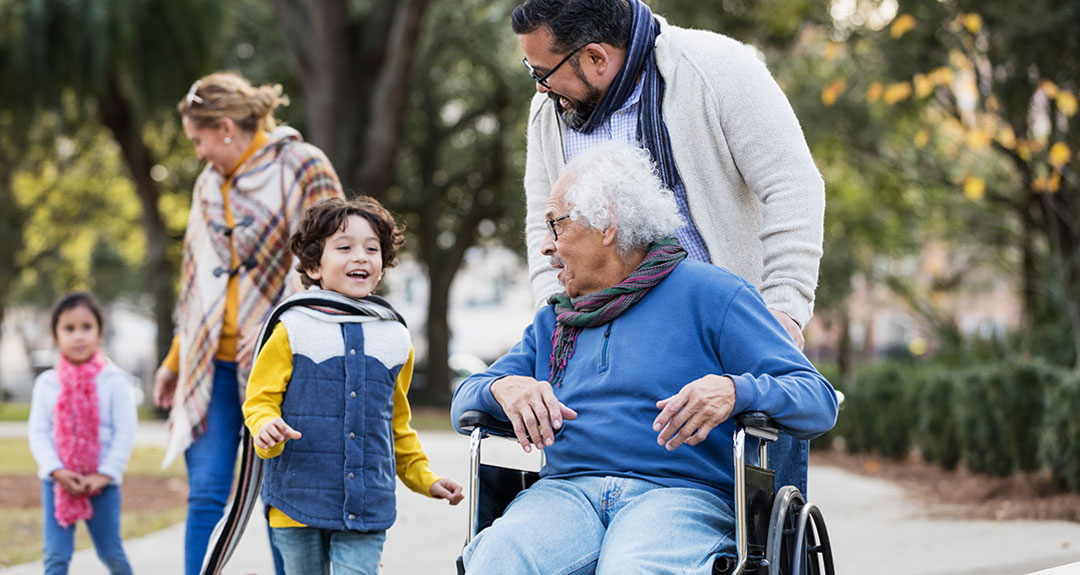 Man in wheelchair looking at a young child approaching him